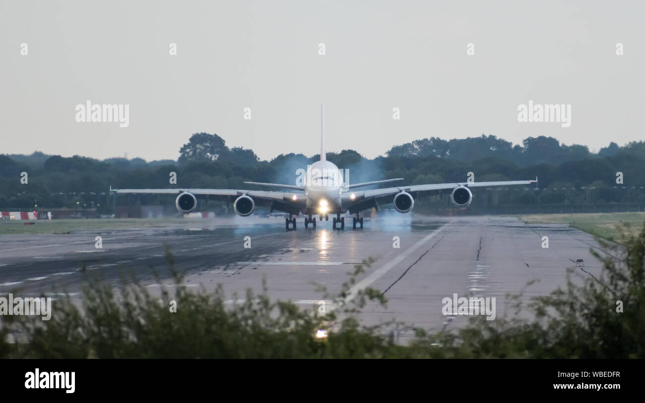 Un Airbus A380-861 Emirates Airlines émet de la fumée des pneus derrière lui-même car il touche le sol, avec la roue avant, toujours dans l'air. Espace copie ci-dessus. Banque D'Images