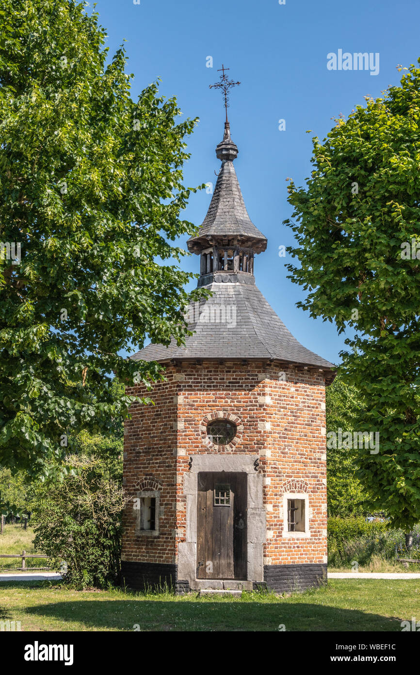 Bokrijk, Belgique - 27 juin 2019 : Chapelle octogonale en brique rouge d'Metsteren avec toit gris foncé sur le dessus et entouré d'arbres. Brown porte est clos Banque D'Images