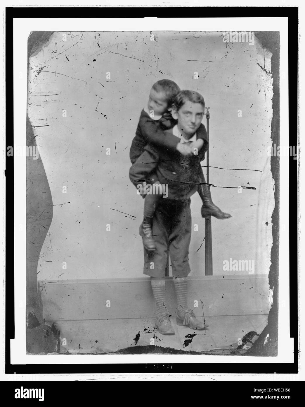 Portrait en pied de deux garçons plus âgés, l'un portant les plus jeunes sur son dos Abstract/moyenne : 1 tirage photographique : ferrotype. Banque D'Images