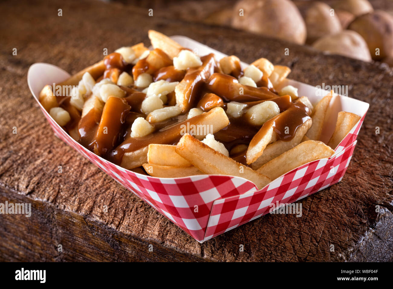 Une portion de la poutine délicieux avec des frites, du fromage en grains et sauce sur une planche en bois rustique. Banque D'Images