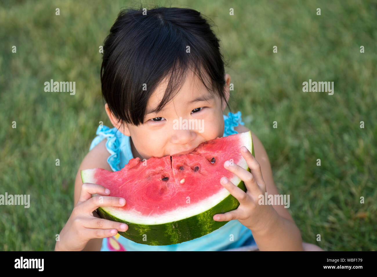 Happy little girl des pastèques dans un jardin Banque D'Images