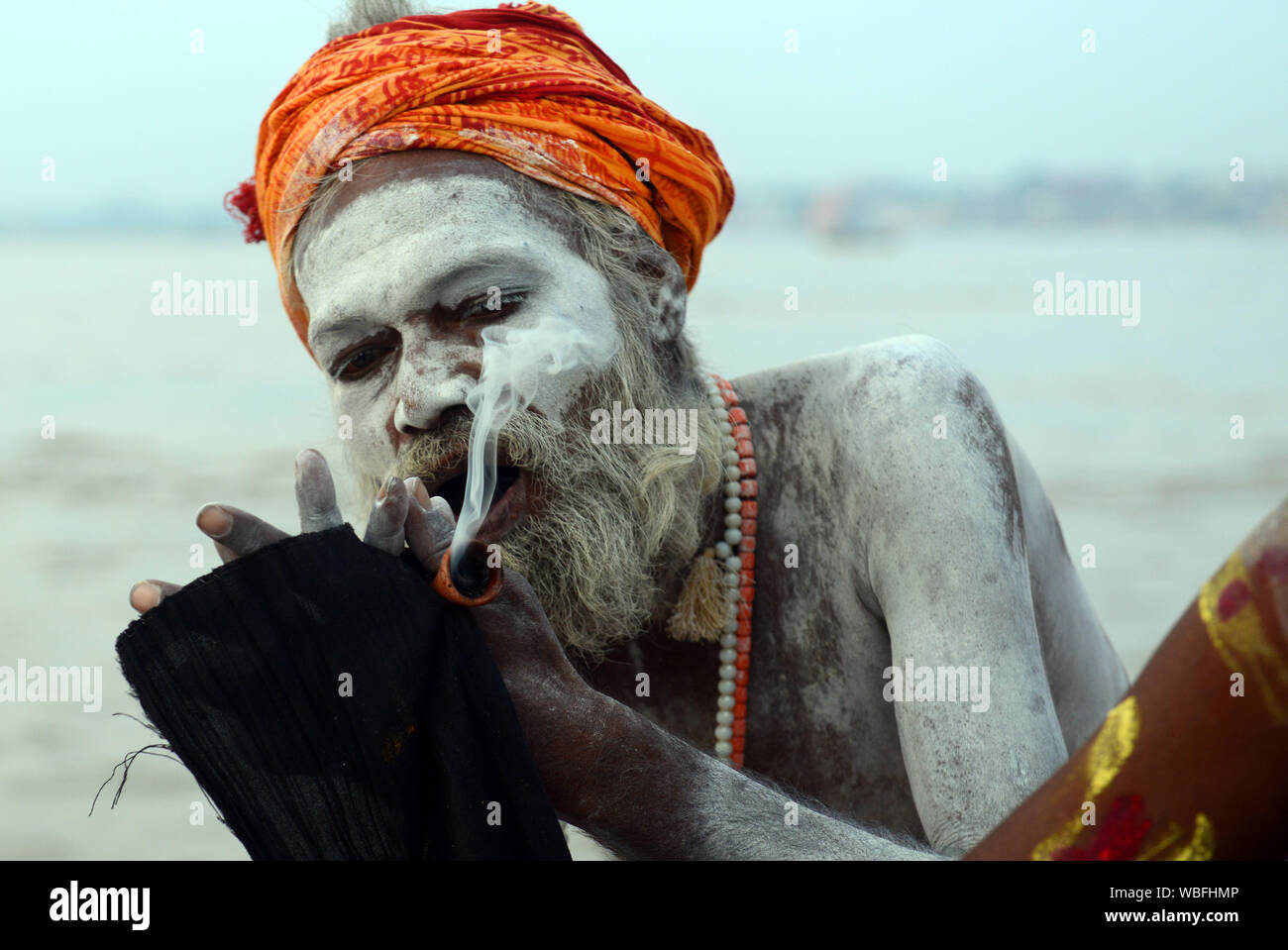 Un Shaiva Sadhu fumeurs Chillum sur le Gange à Varanasi, Inde. Banque D'Images