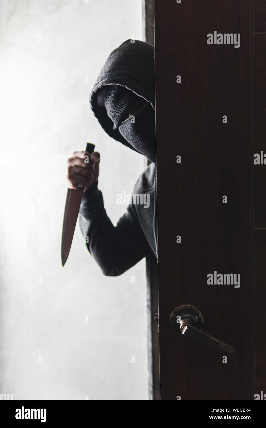 Le voleur est titulaire d'un couteau pour ouvrir la porte de la maison pour vol qualifié. Banque D'Images