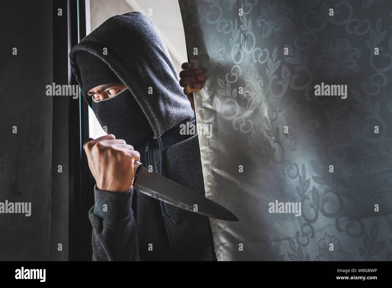 Le voleur est titulaire d'un couteau pour ouvrir la porte de la maison pour vol qualifié. Banque D'Images