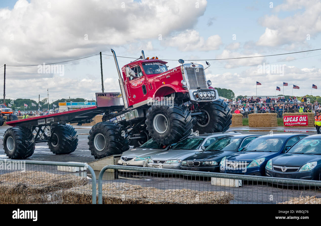 Le grand Pete monster truck écraser une pile de carcasses de voitures en tirant sa remorque sur mesure au cours d'une manifestation à un monster truck show Banque D'Images