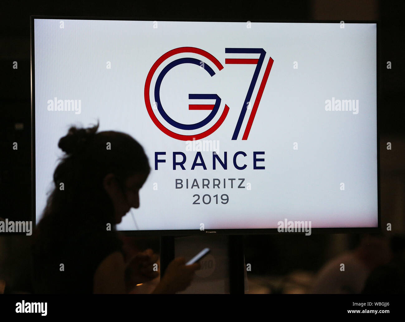 Beijing, la France. Août 25, 2019. Un journaliste se profile sur un écran de télévision au sommet du G7 sur centre à Biarritz, France, le 25 août 2019. Credit : Gao Jing/Xinhua/Alamy Live News Banque D'Images