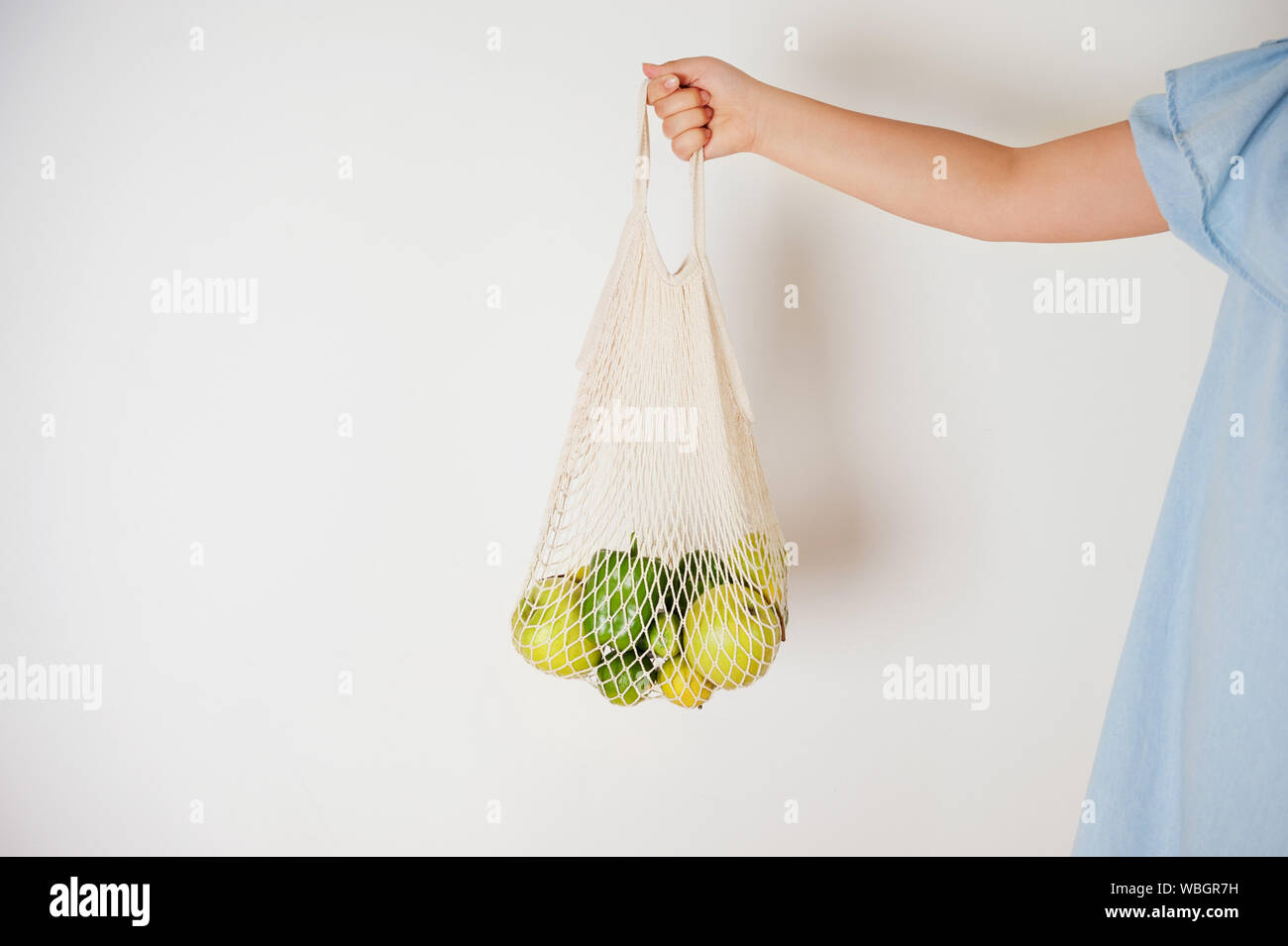 Attente des jeunes adultes string mesh sac rempli de fruits colorés.Concept de la vie naturelle avec zéro déchets ou réutilisable sac eco pour le shopping, Banque D'Images