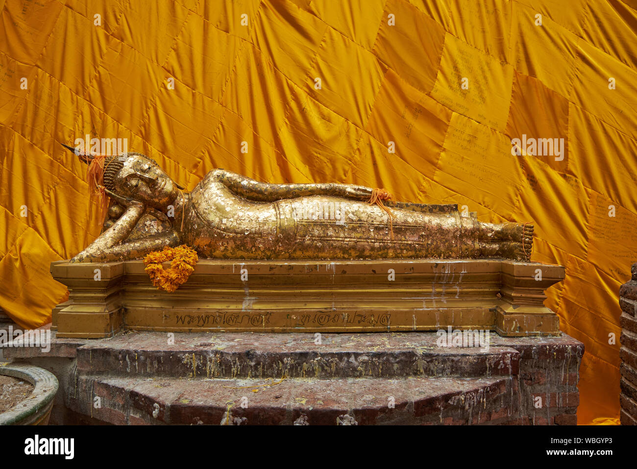 Une petite statue de Bouddha couché en face de l'adorable Bouddha couché, complet avec robe orange, au Wat Khun Inthapramun en Thaïlande, d'Ang Thong. Banque D'Images