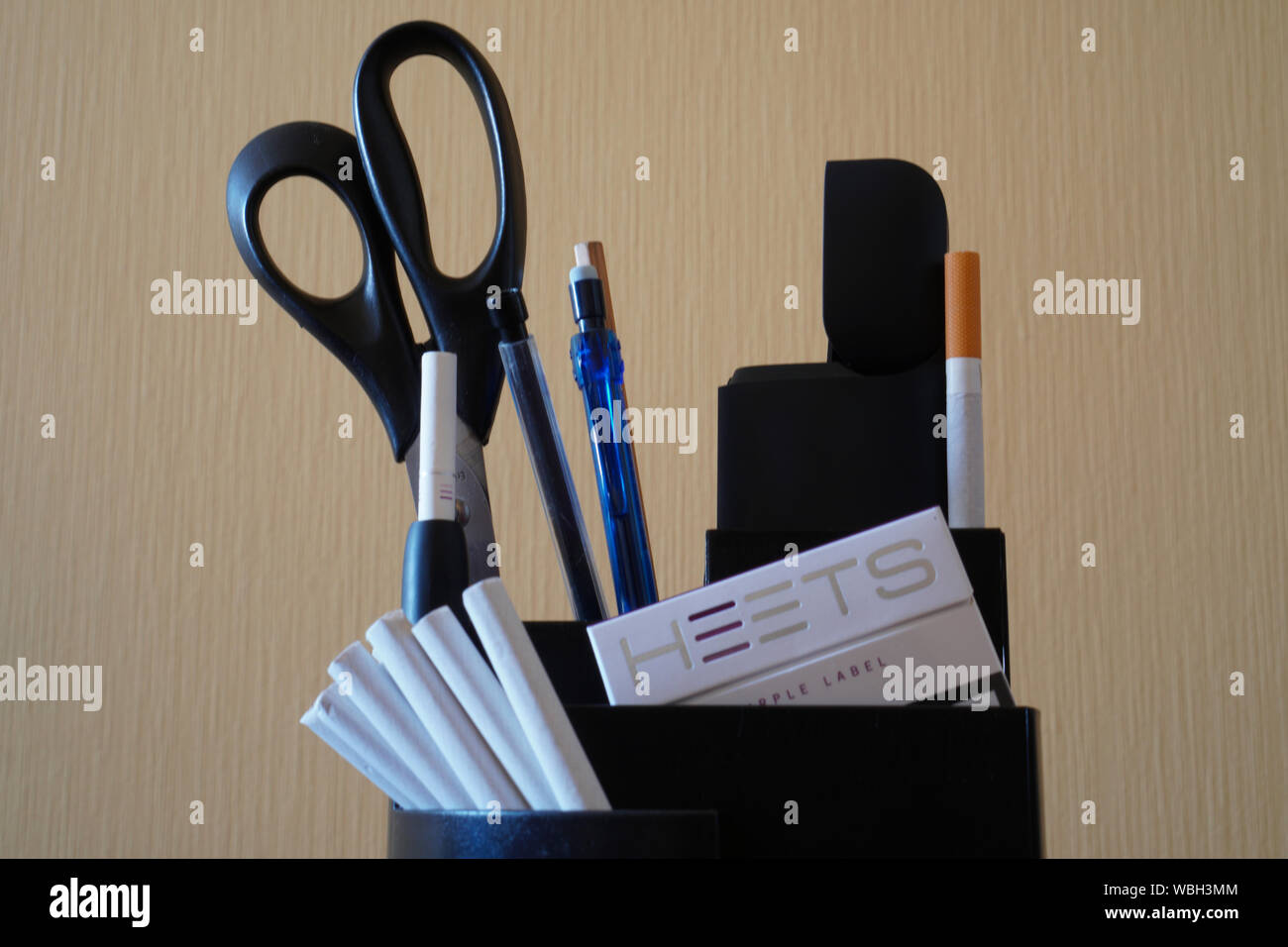 La Russie, Kazan - Août 23, 2019 : Noir appareil Iqos, pâte, cigarrete feuilles bâtonnet de tabac sur le support panier sur le bureau dans le bureau. Le conce Banque D'Images