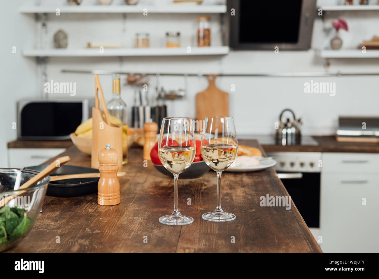 Verres à vin avec du vin, de la nourriture et d'ustensiles de cuisine sur la table dans la cuisine Banque D'Images