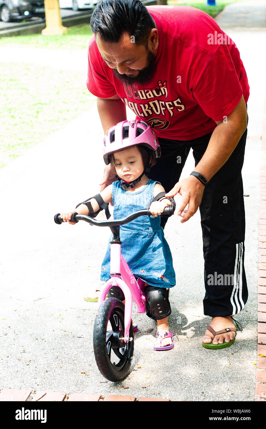 Jeune père de passer du temps avec Mignon Asian 2 ans bébé fille enfant,  père et enfant s'amusant avec balance Bike (vélo de course) sur la nature,  papa te Photo Stock -