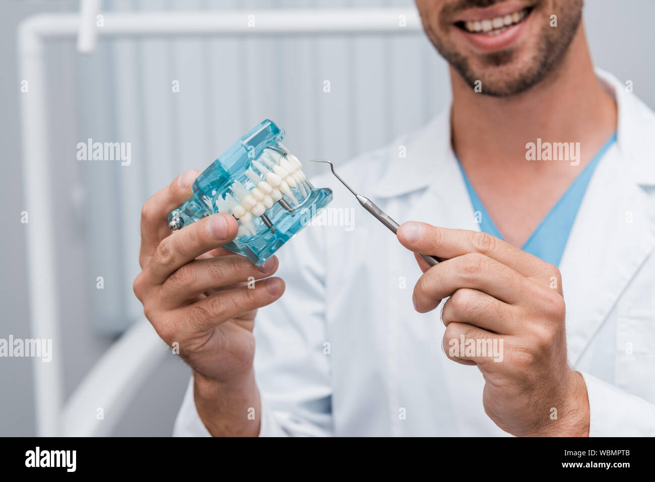 Portrait of cheerful dentiste holding dental instrument et modèle de la dent en mains Banque D'Images