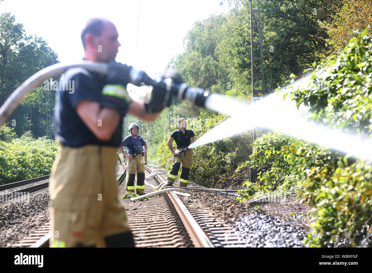 Bottrop, Allemagne. Août 27, 2019. Les pompiers sont debout à un remblai sur une ligne de trains de marchandises et d'extinction d'un incendie. Le remblai de la ligne de train de marchandises était en feu à plusieurs endroits, plusieurs milliers de mètres carrés de remblai de chemin de fer ont été touchés. Credit : Roland Weihrauch/dpa/Alamy Live News Banque D'Images