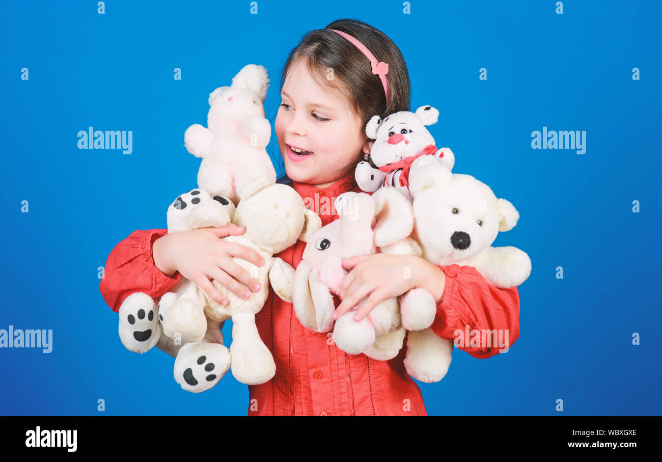 Enfance heureuse. Petite fille jouer avec doudou ours. Lot de jouets dans ses mains. Concept de la petite enfance. La collecte de jouets passe-temps. Chérir les souvenirs de l'enfance. Petite fille visage souriant avec des jouets. Banque D'Images