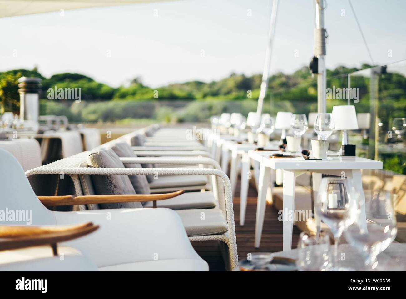 Mise au point sélective de fauteuils blancs autour de tables blanches avec verres à vin et lampes sur eux Banque D'Images