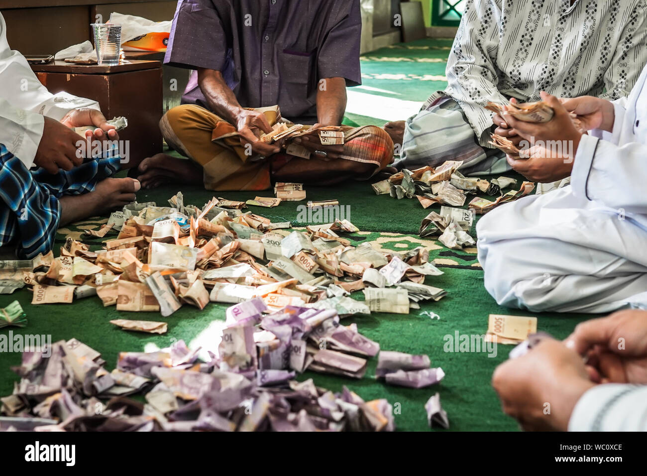 Un groupe d'hommes en comptant la charité de l'argent dans une mosquée. Banque D'Images