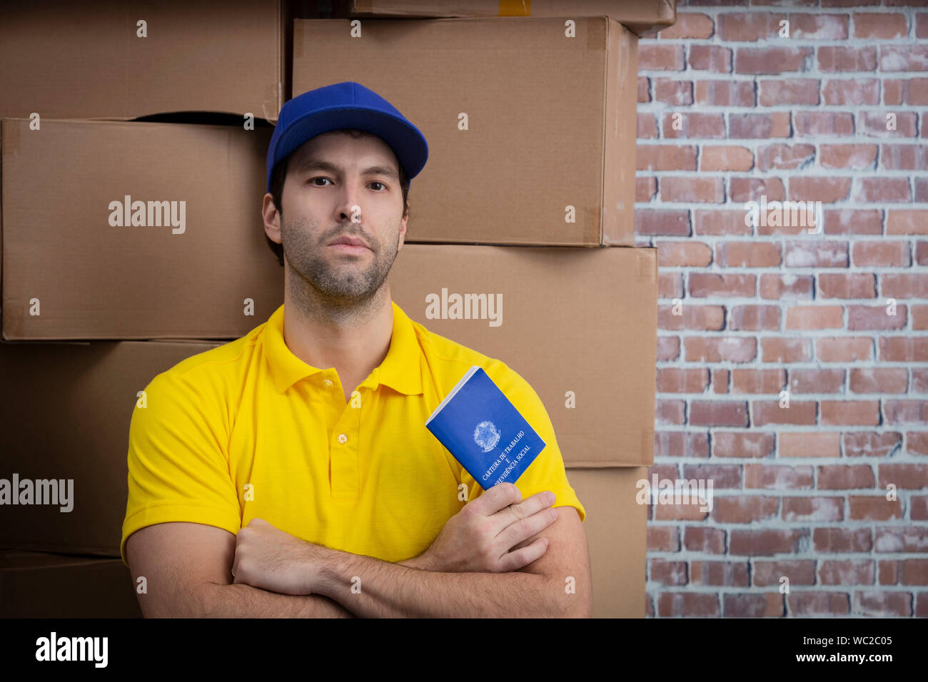 Mailman brésilien tenant son carnet de travail sécurité sociale brésilienne document, dans un dépôt avec un beaucoup de boîtes. Banque D'Images