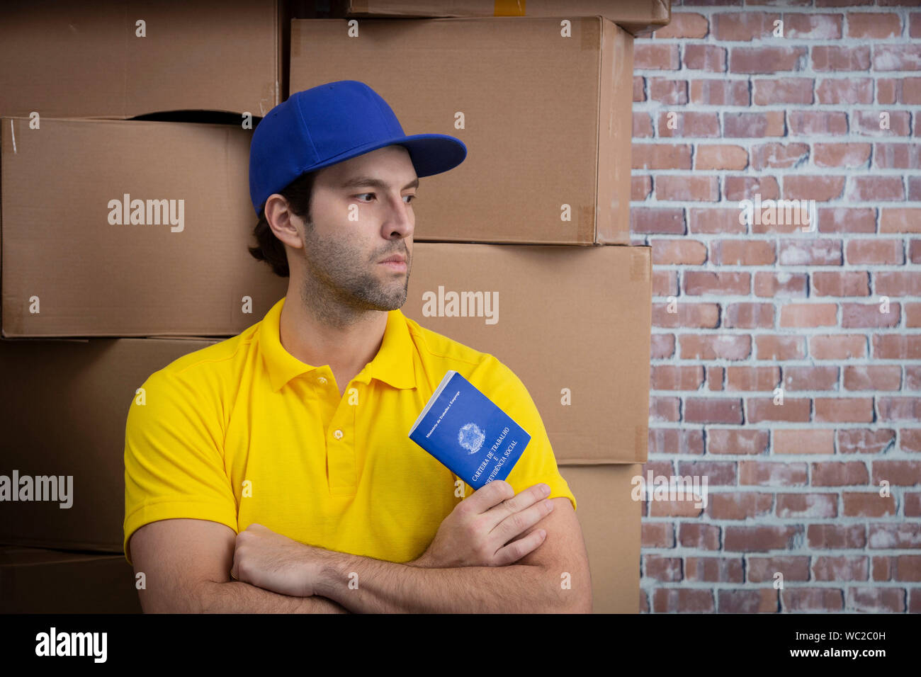 Mailman brésilien tenant son carnet de travail sécurité sociale brésilienne document, dans un dépôt avec un beaucoup de boîtes. Banque D'Images