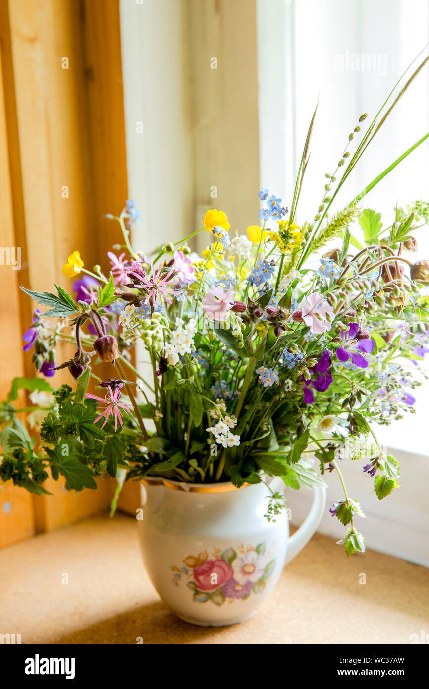 Style Vintage flower bouquet fait de fleurs sauvages trouvés en forêt et prairie, debout dans le vieux pot de crème sur le rebord de fenêtre, l'été dans la maison de grand maman con Banque D'Images