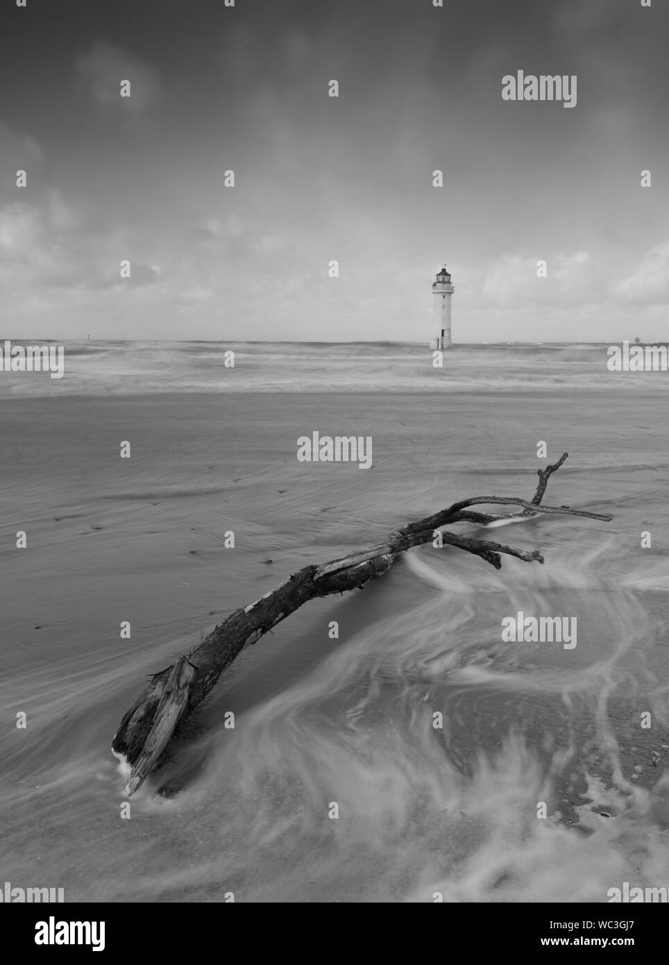 Phare dans la mer, avec du bois flotté en premier plan Banque D'Images