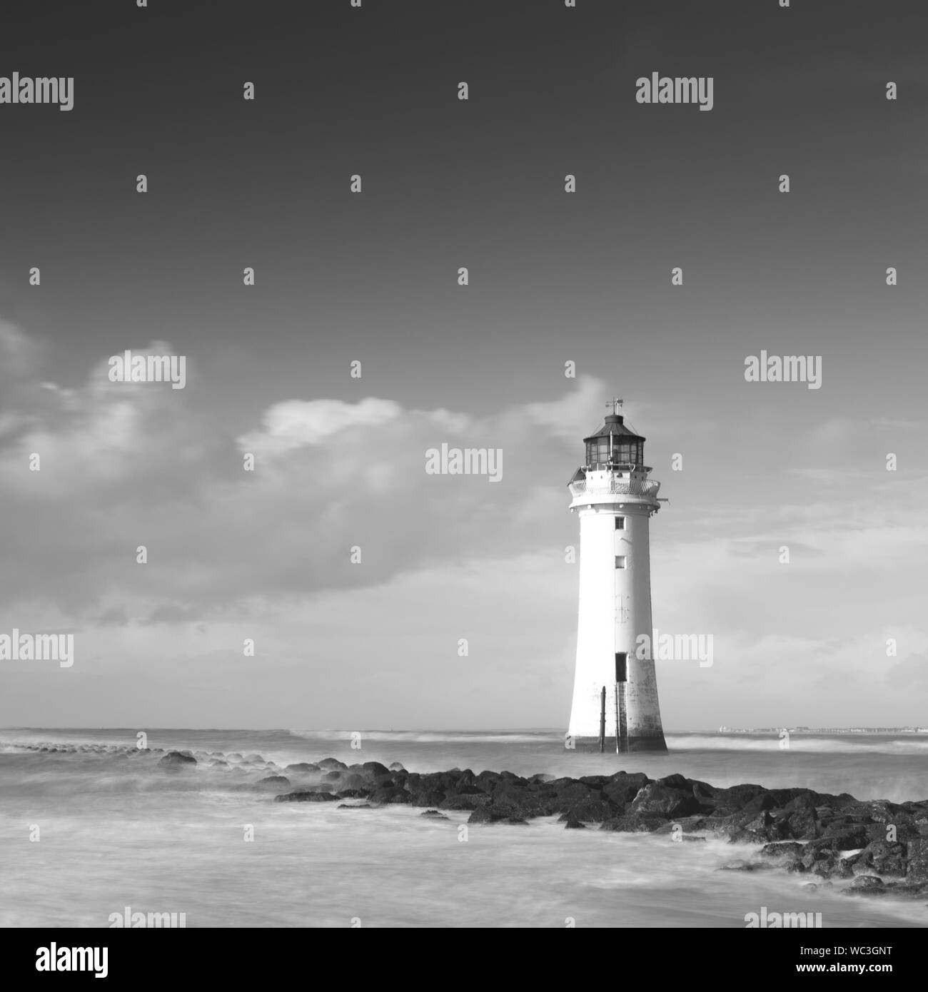 Phare avec cloudbank dérive et des roches couvertes d'algues Banque D'Images
