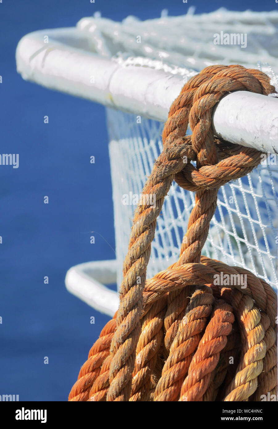 Corde orange avec un nœud à une main courante d'un navire. Le bleu de la mer en arrière-plan Banque D'Images