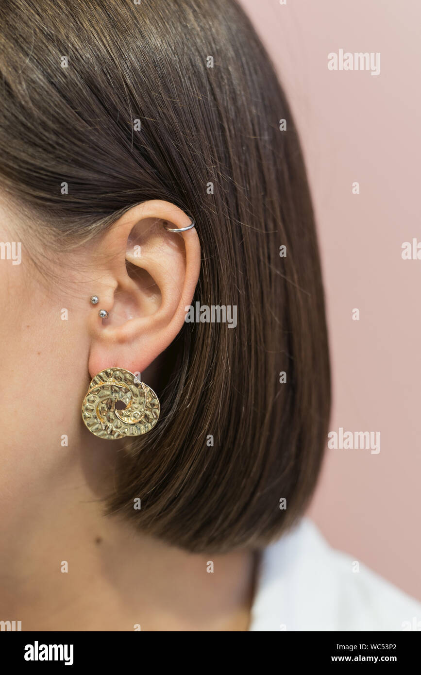 Ronde élégante à la mode d'oreilles en or sur la fille s'oreille avec Bob coupe. Fond rose pastel. Banque D'Images