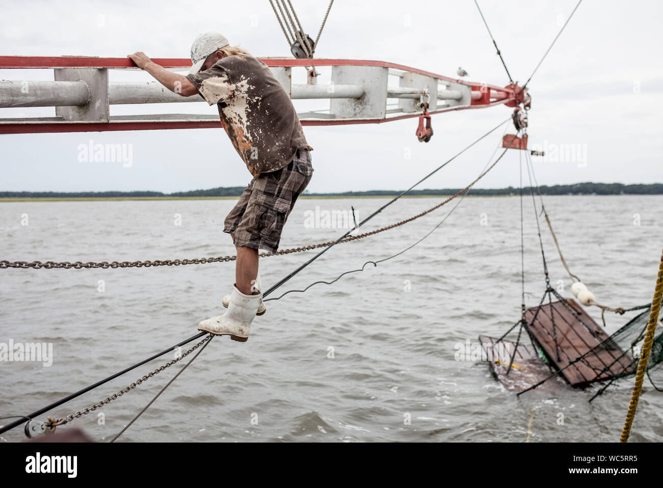 Matelot de l'escalade sur le bateau de pêche de gréement Banque D'Images