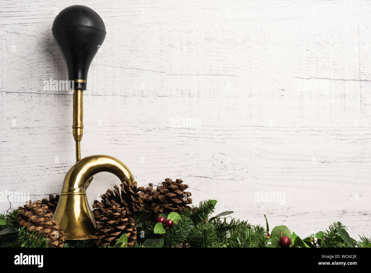 Concept démodé Noël peint en blanc avec fond en bois rustique et antique corne laiton automobile en caoutchouc noir avec ampoule et verdure avec p Banque D'Images