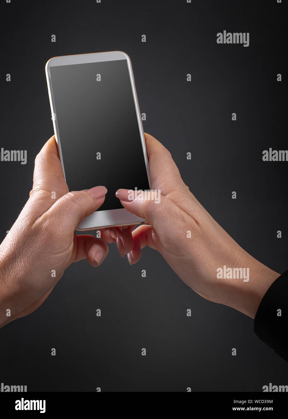 Téléphone mobile dans les mains sur un fond noir Banque D'Images