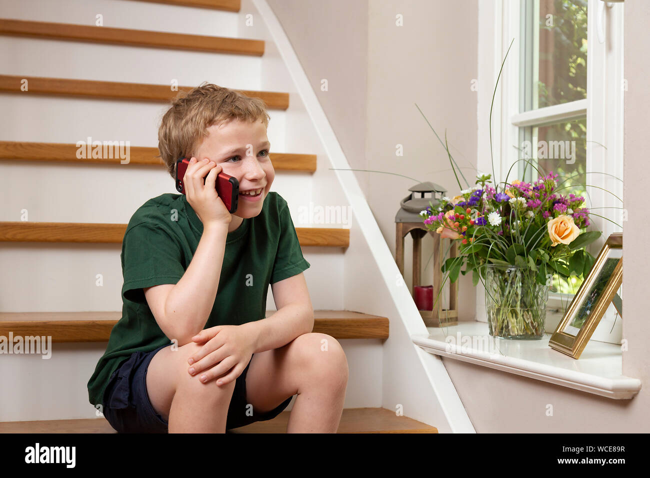 Garçon, 8 ans, faisant appel à la maison avec le smartphone, Allemagne Banque D'Images