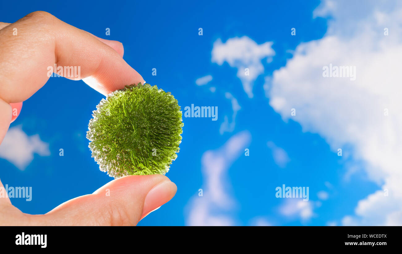 Moldavite. Vert Rare gem météorique dans la main de collecteur. Ciel bleu. Pierre précieuse magique d'origine cosmique. Matière transparente avec l'apparition de la mousse. Banque D'Images