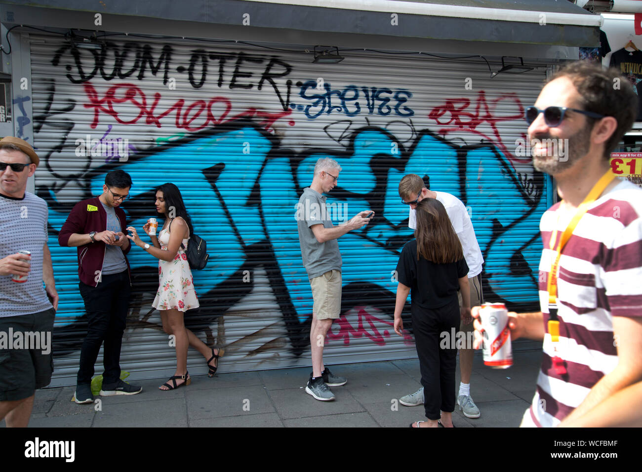 Notting Hill Carnival, 25 août 2019.Les jeunes dans la rue avec des téléphones et des canettes de bière. Banque D'Images