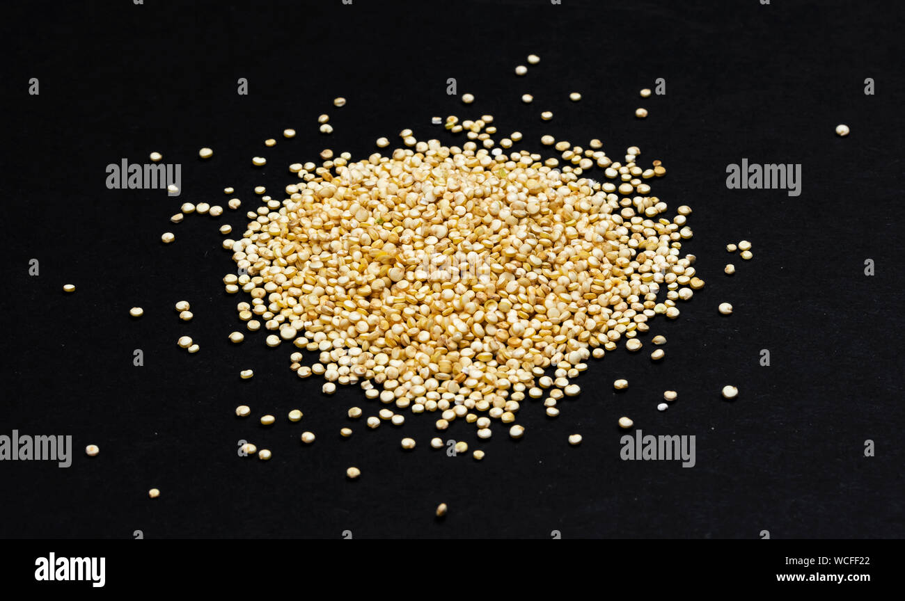 Tas de graines de quinoa isolé sur fond noir close up, vue du dessus Banque D'Images
