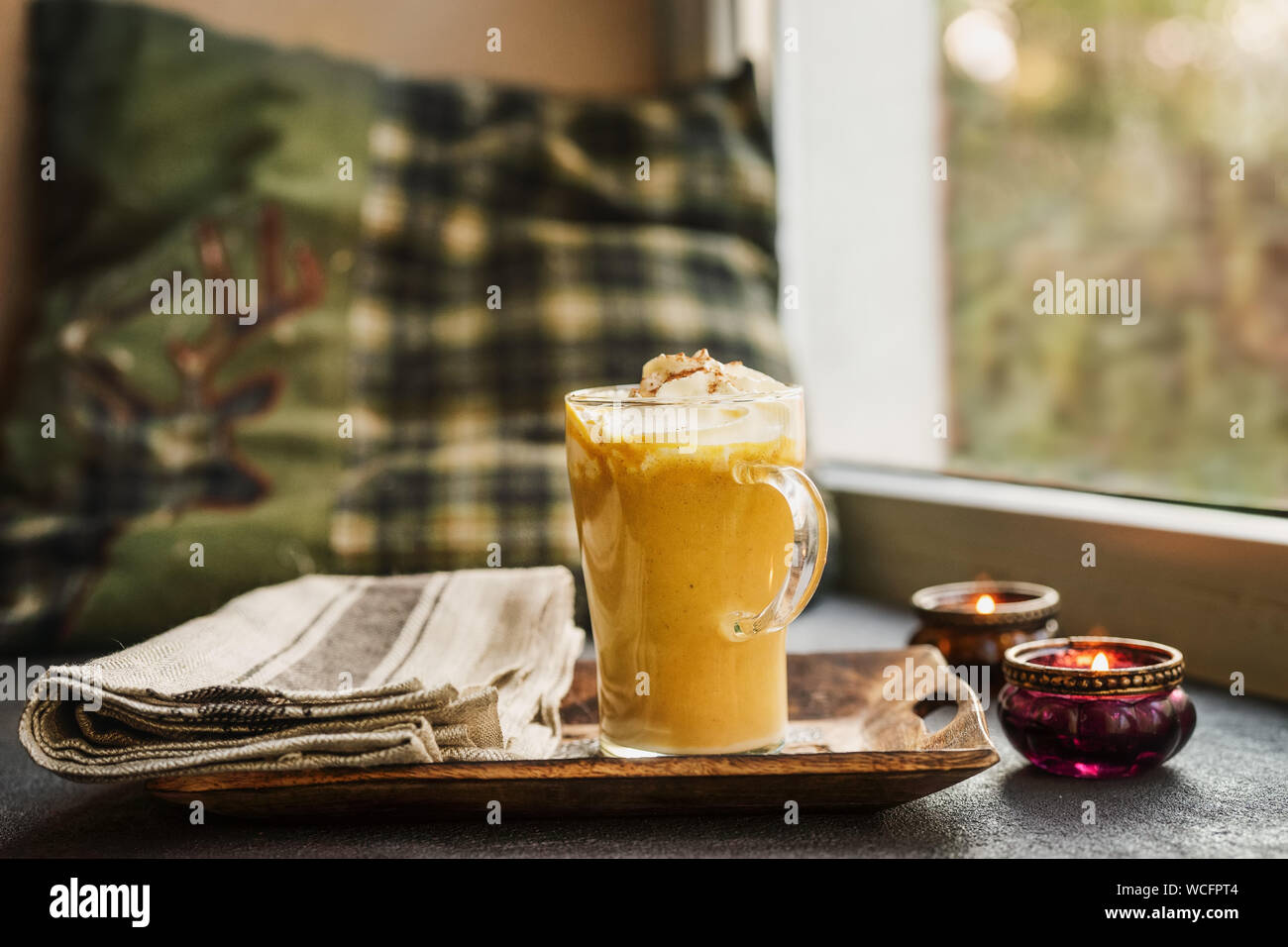 Une tasse en verre de pumpkin spice latte près d'une fenêtre Banque D'Images