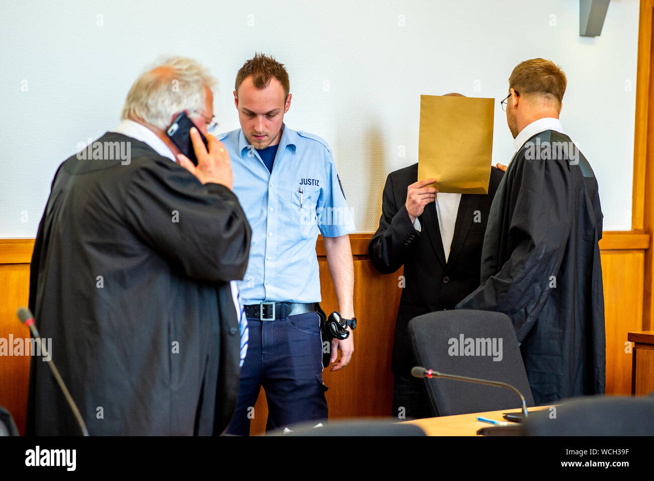 Hagen, Allemagne. Août 28, 2019. Le défendeur Sven S. est conduit dans la salle d'audience par un fonctionnaire judiciaire et converse avec son défenseur Nikolai Odebralski (droite). Après la mort violente d'un un an à Plettenberg en Rhénanie du Nord-Westphalie, le jury a condamné l'Hagen père adoptif, à douze ans de prison pour homicide involontaire. Crédit : David Inderlied/dpa/Alamy Live News Banque D'Images