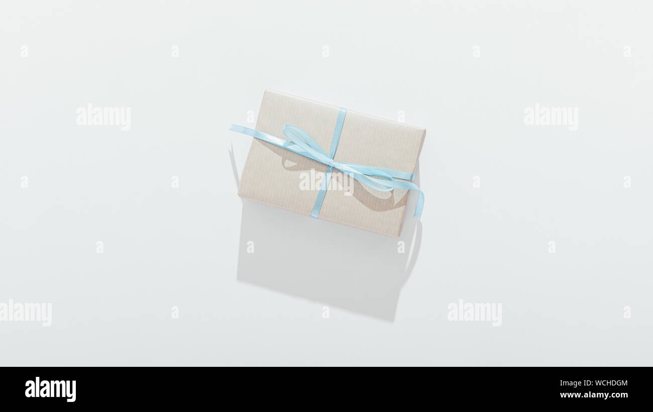 Boîte-cadeau attaché avec du ruban bleu ombre longue coulée sur fond blanc, vue de dessus. Banque D'Images