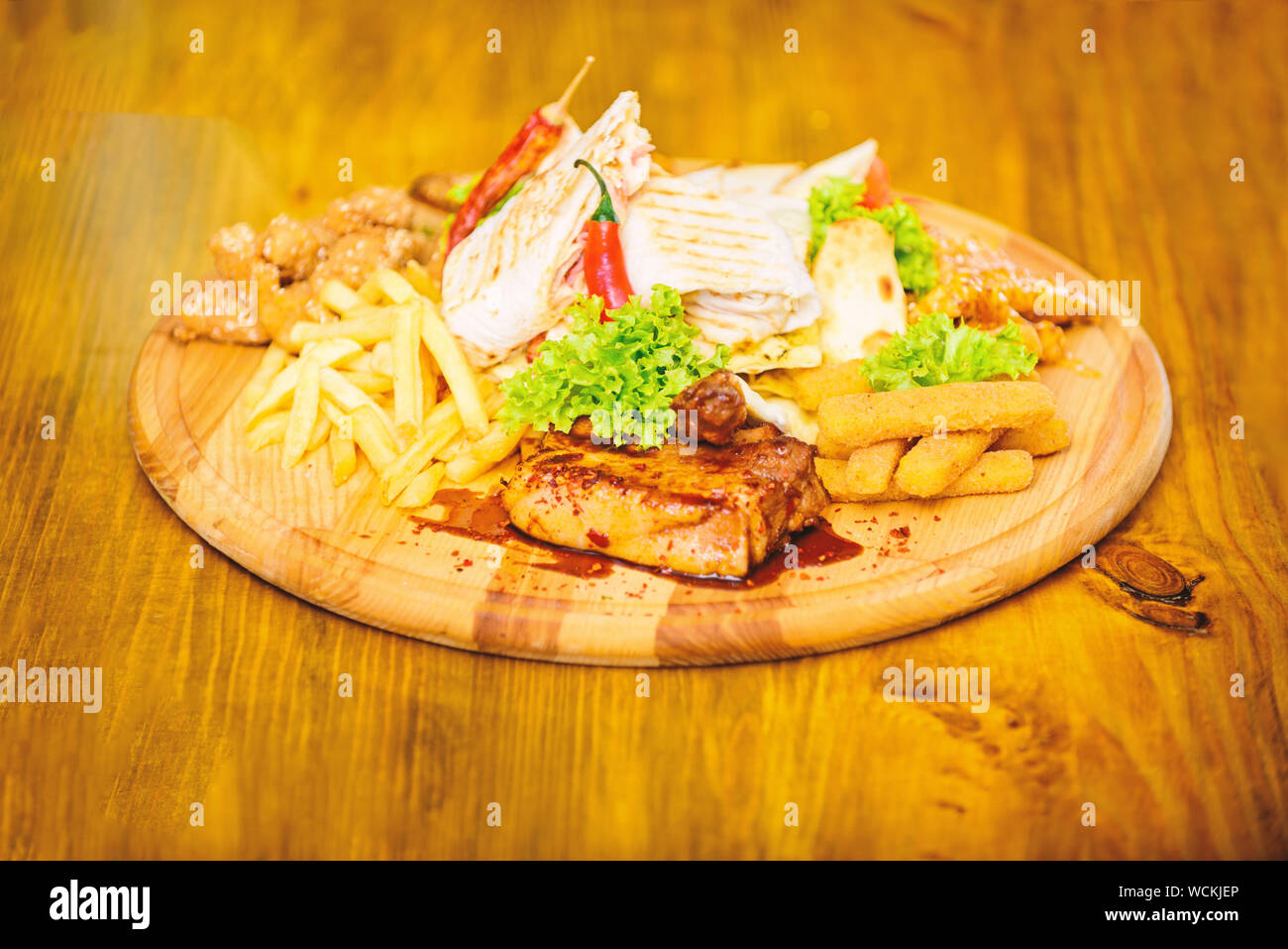 Snack pour la bière. Les repas au restaurant. Planche de bois frites et bâtonnets de poisson viande burrito steak servi avec une salade. Menu snack-bar. Profitez de votre repas. Snack de viande pour le groupe d'amis. De délicieux en-cas savoureux. Banque D'Images