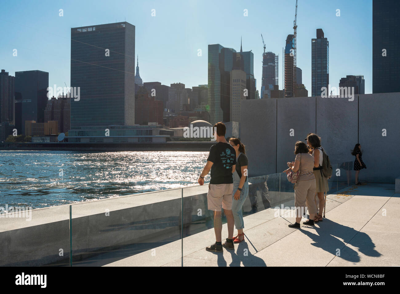 New York touristes, vue des touristes se tenant dans le parc des quatre libertés sur Roosevelt Island en regardant de l'autre côté de la rivière East vers Midtown Manhattan New York Banque D'Images