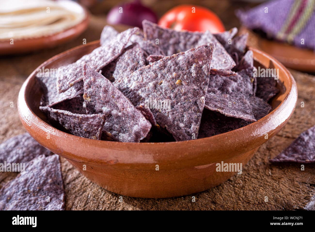Un bol de délicieuse tortilla chips nacho maïs bleu dans un Oaxcan authentique bol de céramique sur bois rustique. Banque D'Images