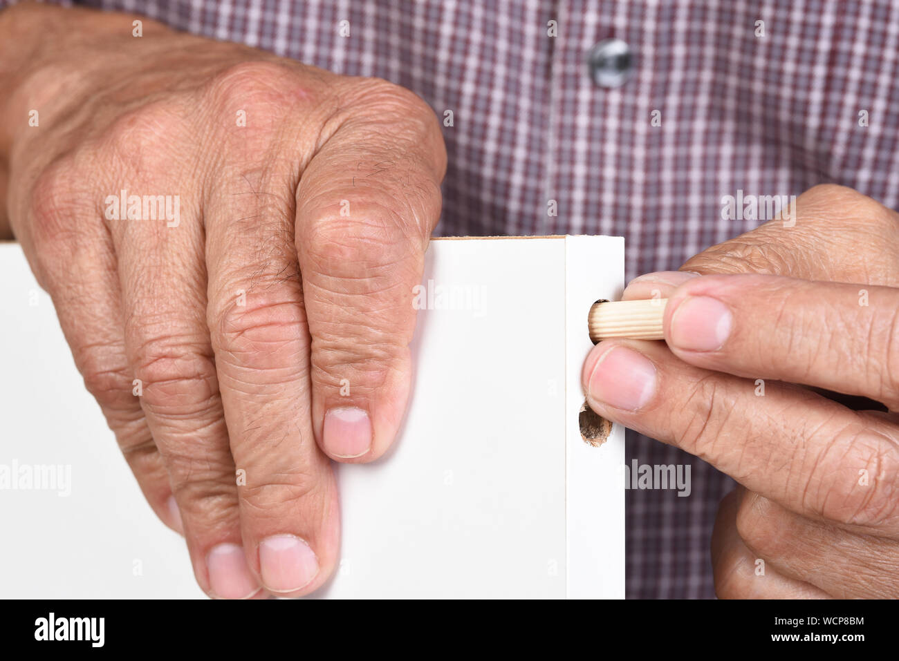 Libre d'un homme de l'assemblage d'un meuble à monter. Le travailleur est l'insertion d'une cheville en bois dans un avant-trou. Banque D'Images