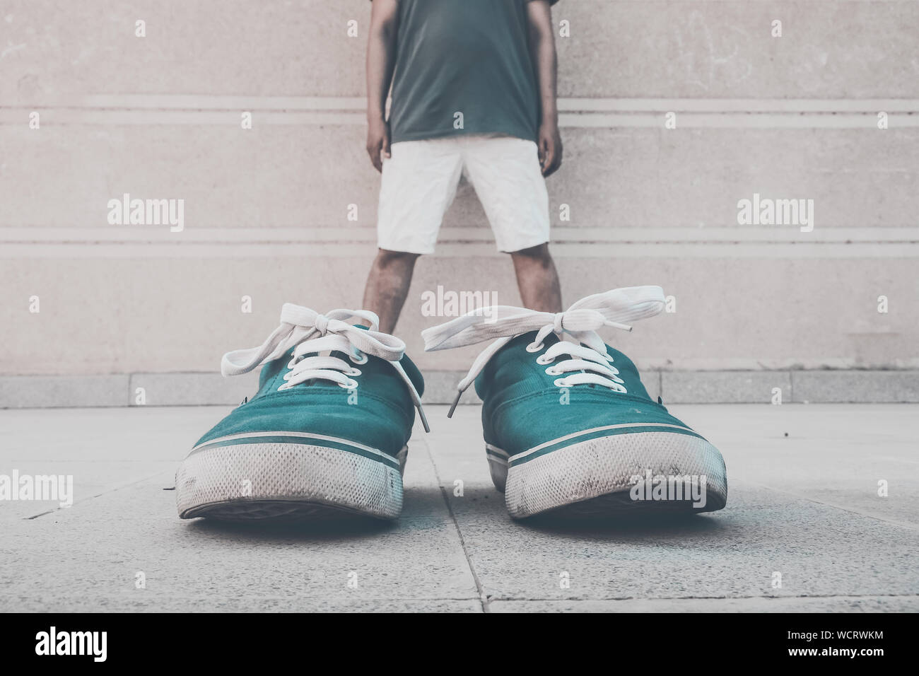 Illusion d'optique d'un homme portant des chaussures contre le mur vert  Photo Stock - Alamy
