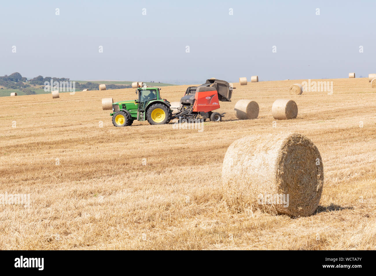 Près de Devils Dyke, Brighton, Royaume-Uni ; 26 août 2019 ; Farmer dans un tracteur à l'aide de bottes de foin sur un jour brumeux lumineux Banque D'Images