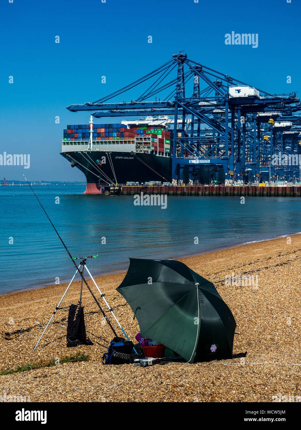 Felixstowe Container Port - le navire à conteneurs d'or ne cesse de charger du fret au port de Felixstowe UK regardé par un pêcheur de plage. Banque D'Images