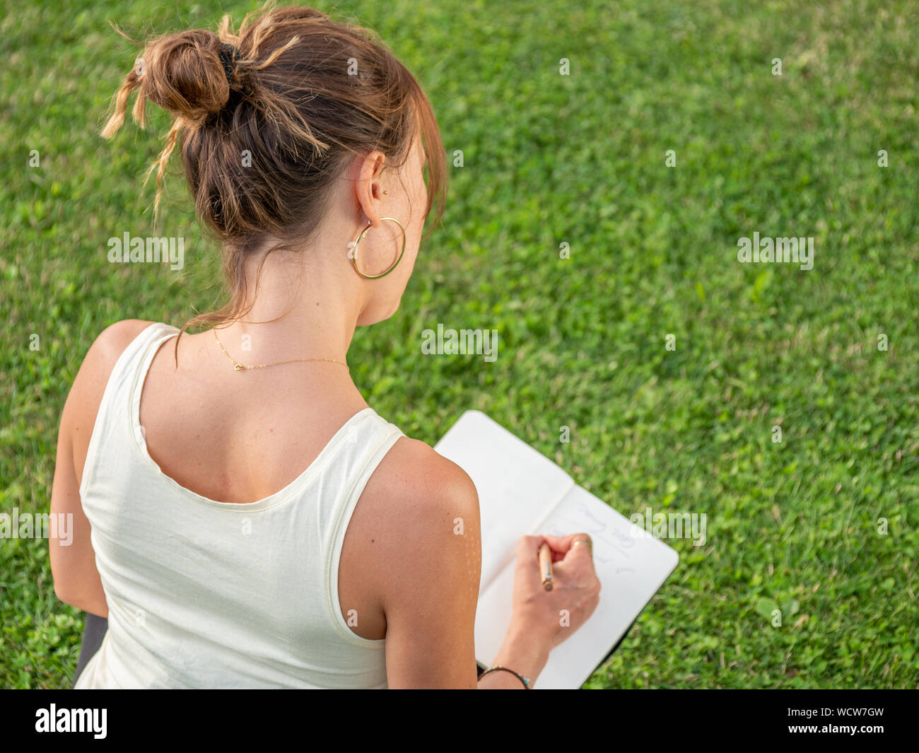 Close-up of woman in Green grass et l'écriture de journal Calendrier Calendrier Banque D'Images