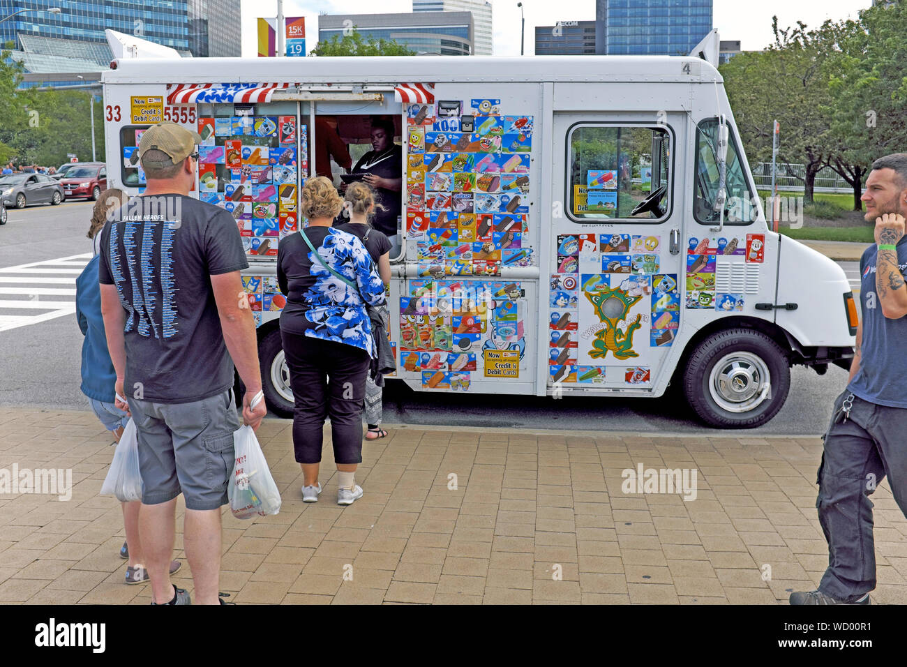 Les adultes attendent en ligne un camion de glace mobile côté rue lors d'une chaude journée d'été à Washington, DC, USA. Banque D'Images