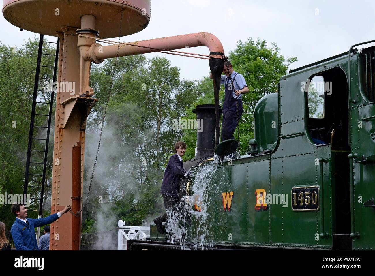 Les jeunes bénévoles remplir les réservoirs d'eau de classe 14XX GWR 1450 réservoir du moteur à Didcot Railway Centre, Oxfordshire Banque D'Images