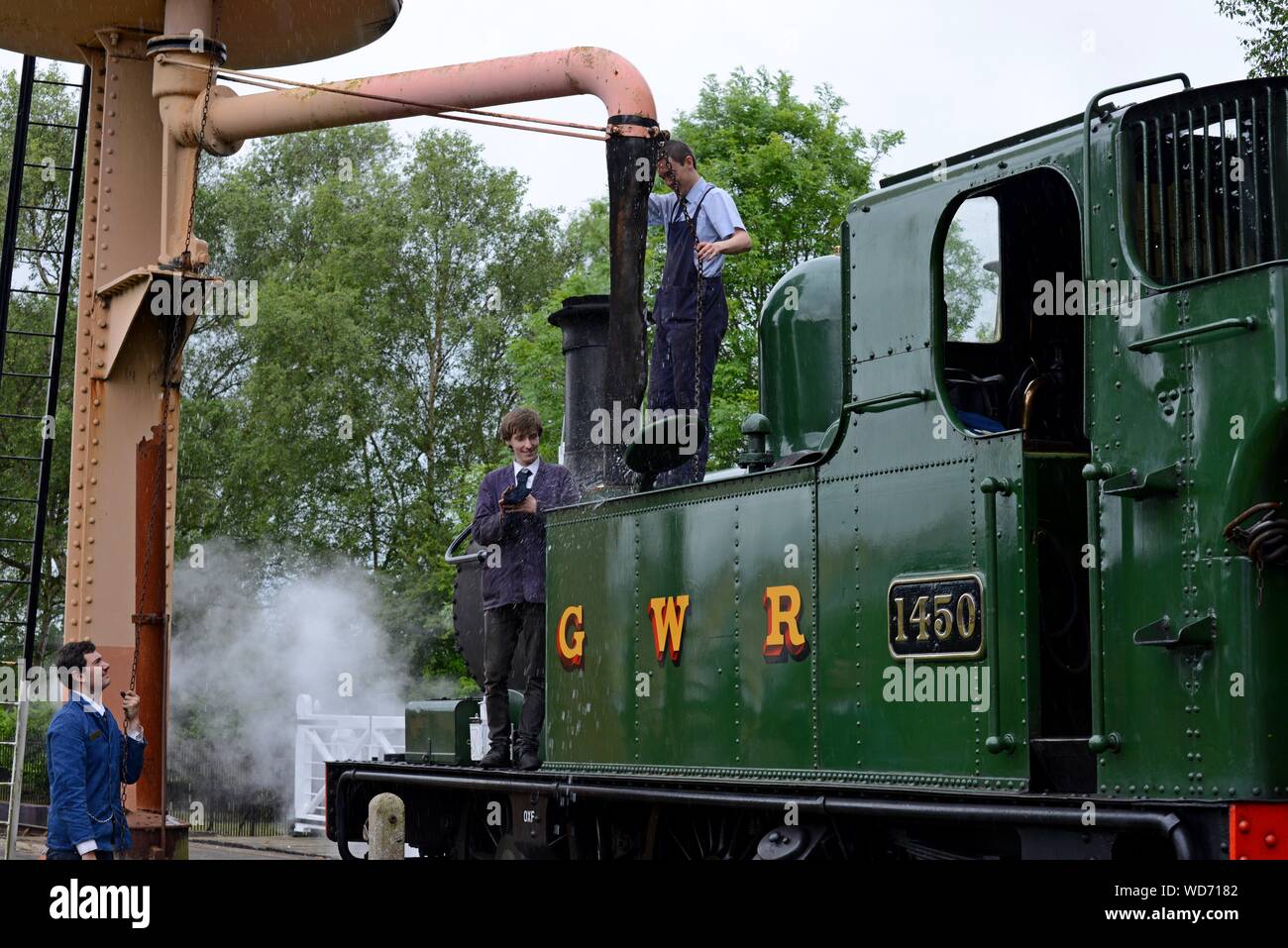 Les jeunes bénévoles remplir les réservoirs d'eau de classe 14XX GWR 1450 réservoir du moteur à Didcot Railway Centre, Oxfordshire Banque D'Images