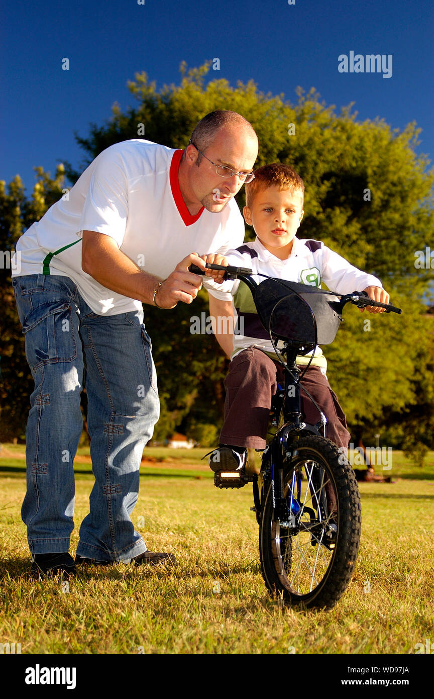 Père, c'est enseigner à son fils pour circuler à bicyclette dans le parc Banque D'Images