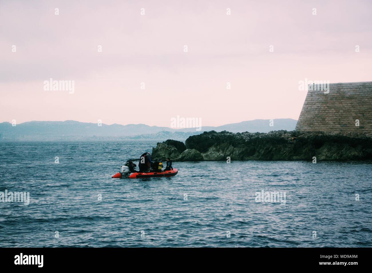 Gros plan de personnes dans un bateau gonflable sur le plan d'eau près d'une petite falaise Banque D'Images
